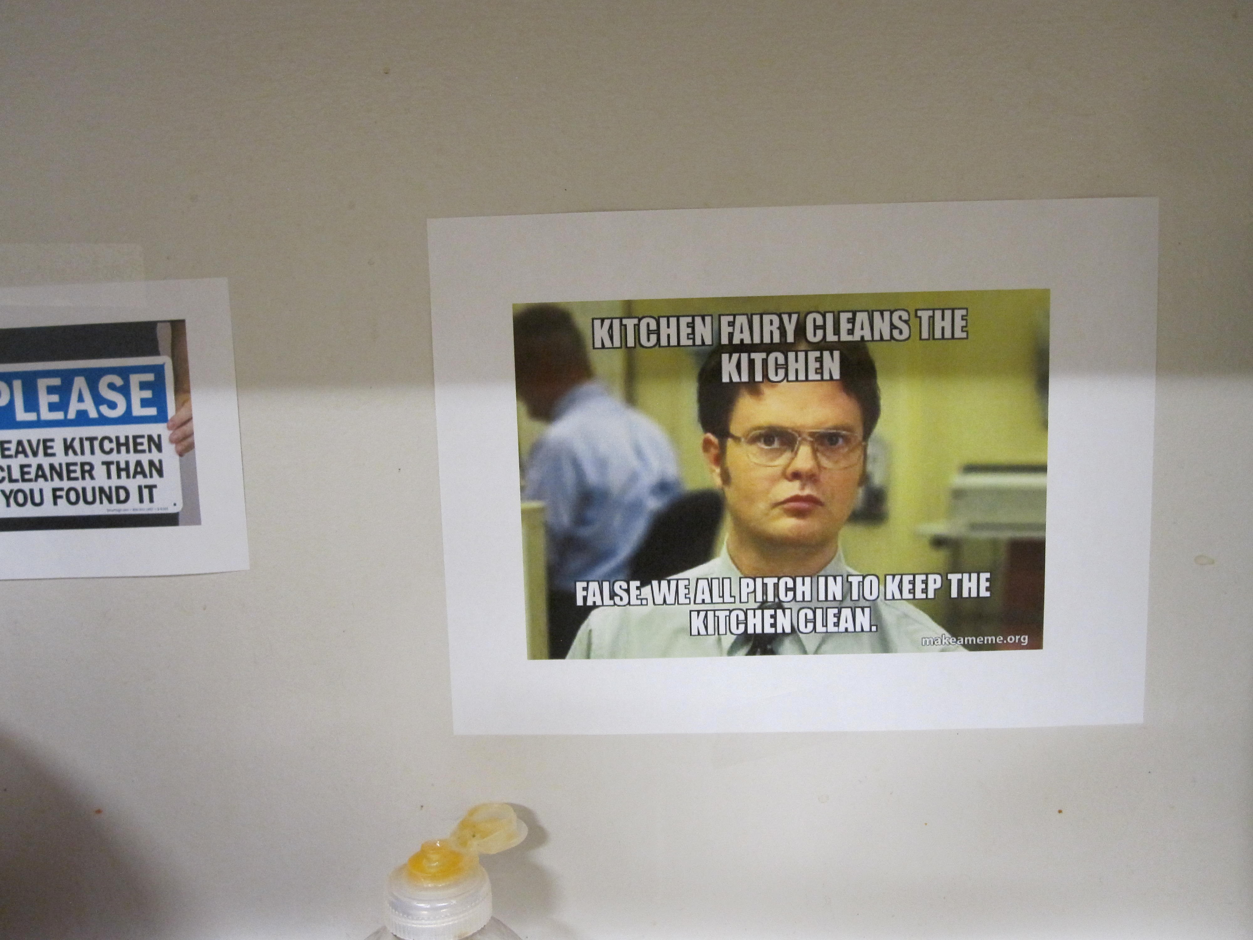 a printed out meme of Dwight from the office taped to a wall encouraging viewers to clean the kitchen