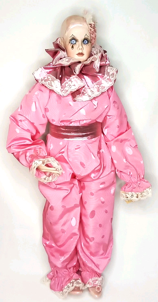 a jester doll with piercing blue eyes and a pink silk outfit