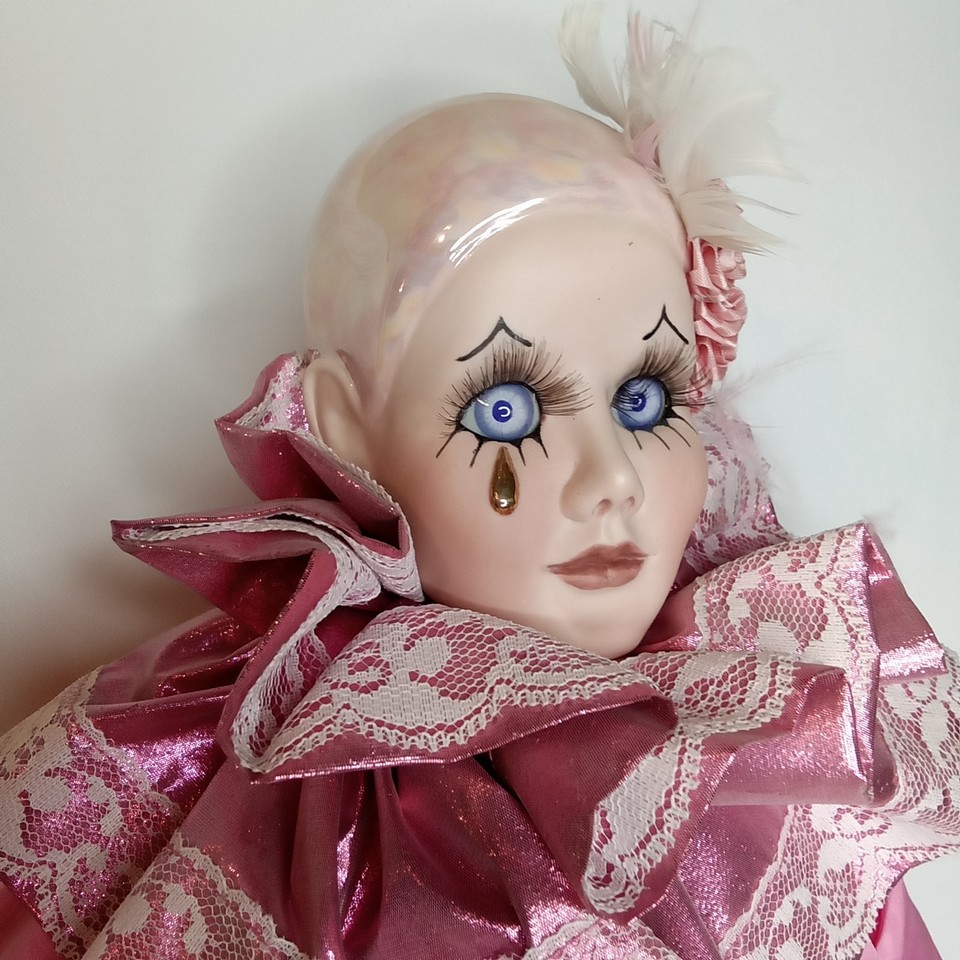 close-up of a jester doll with piercing blue eyes and a pink silk outfit