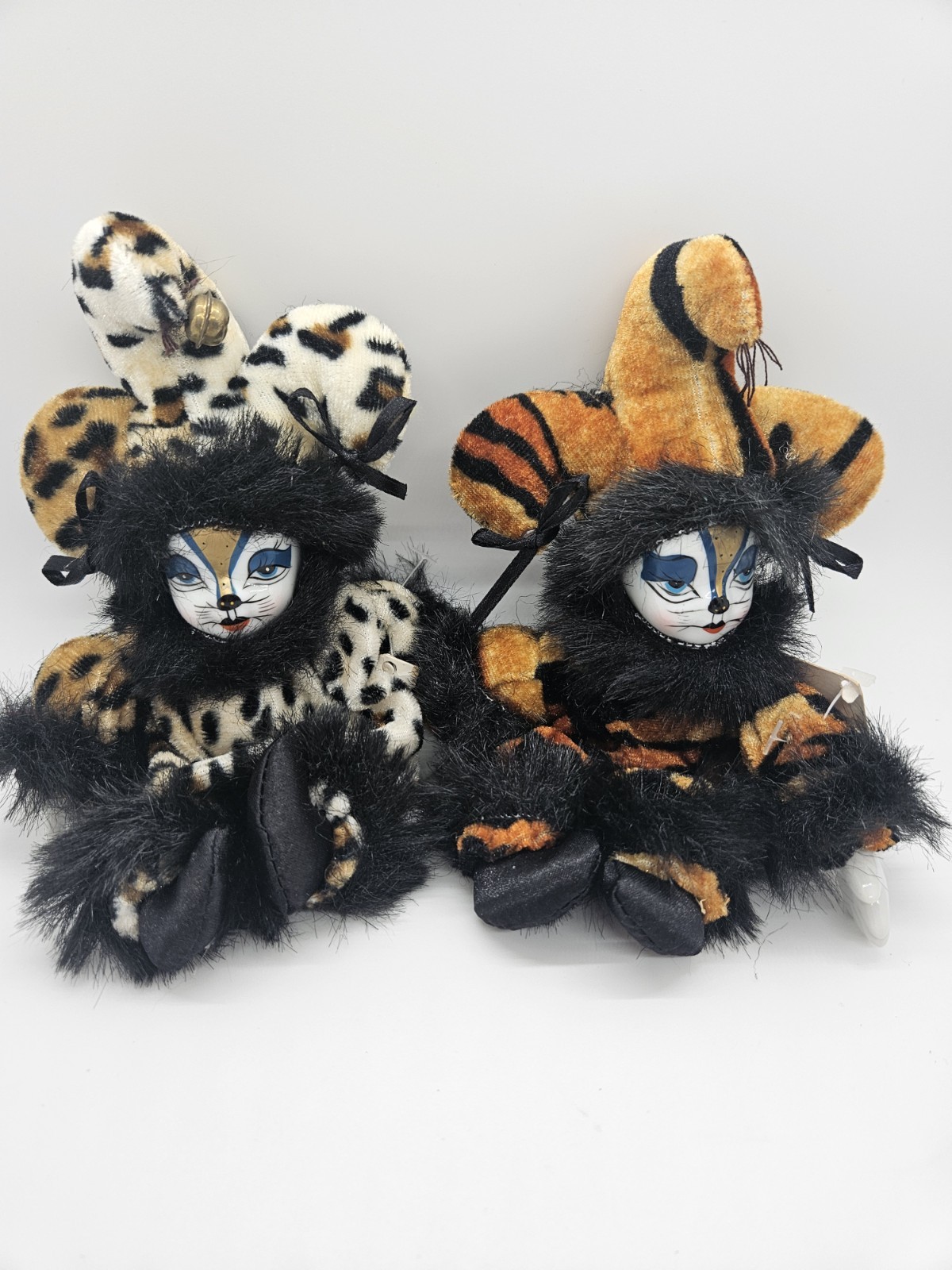 two porcelain-faced cat clowns with soft bodies sit side by side