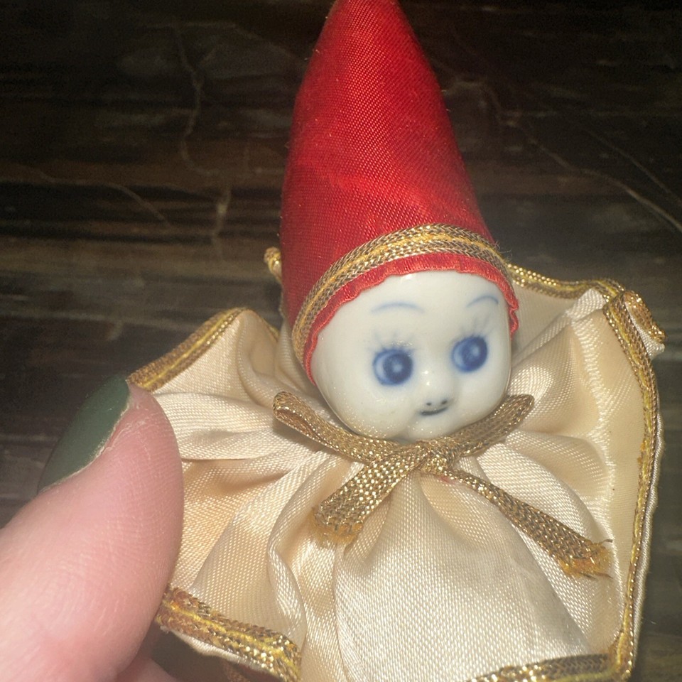 a porcelain faced clown with an impish expression and a round red body