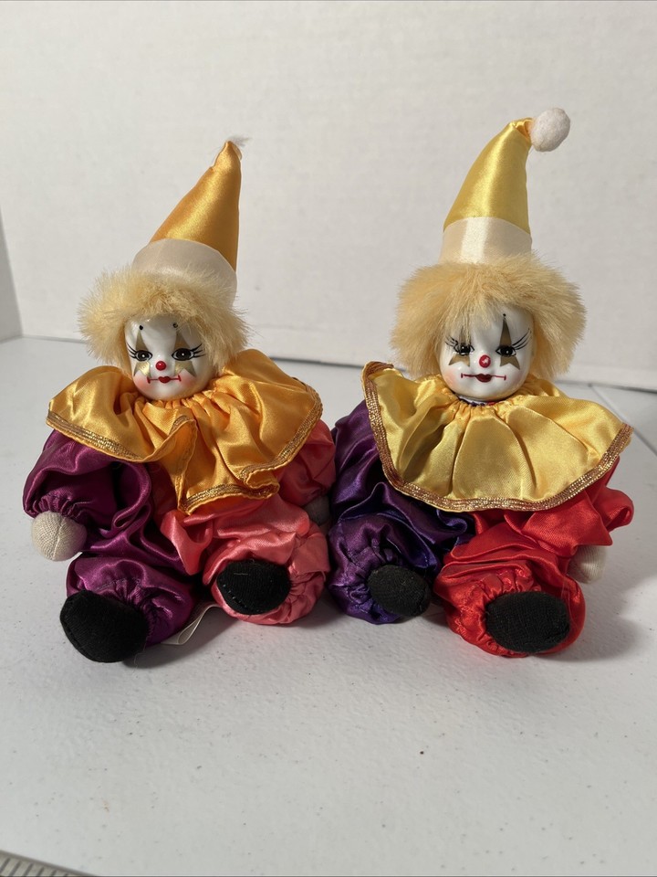 two nearly identical porcelain-faced softbody clowns sit side by side